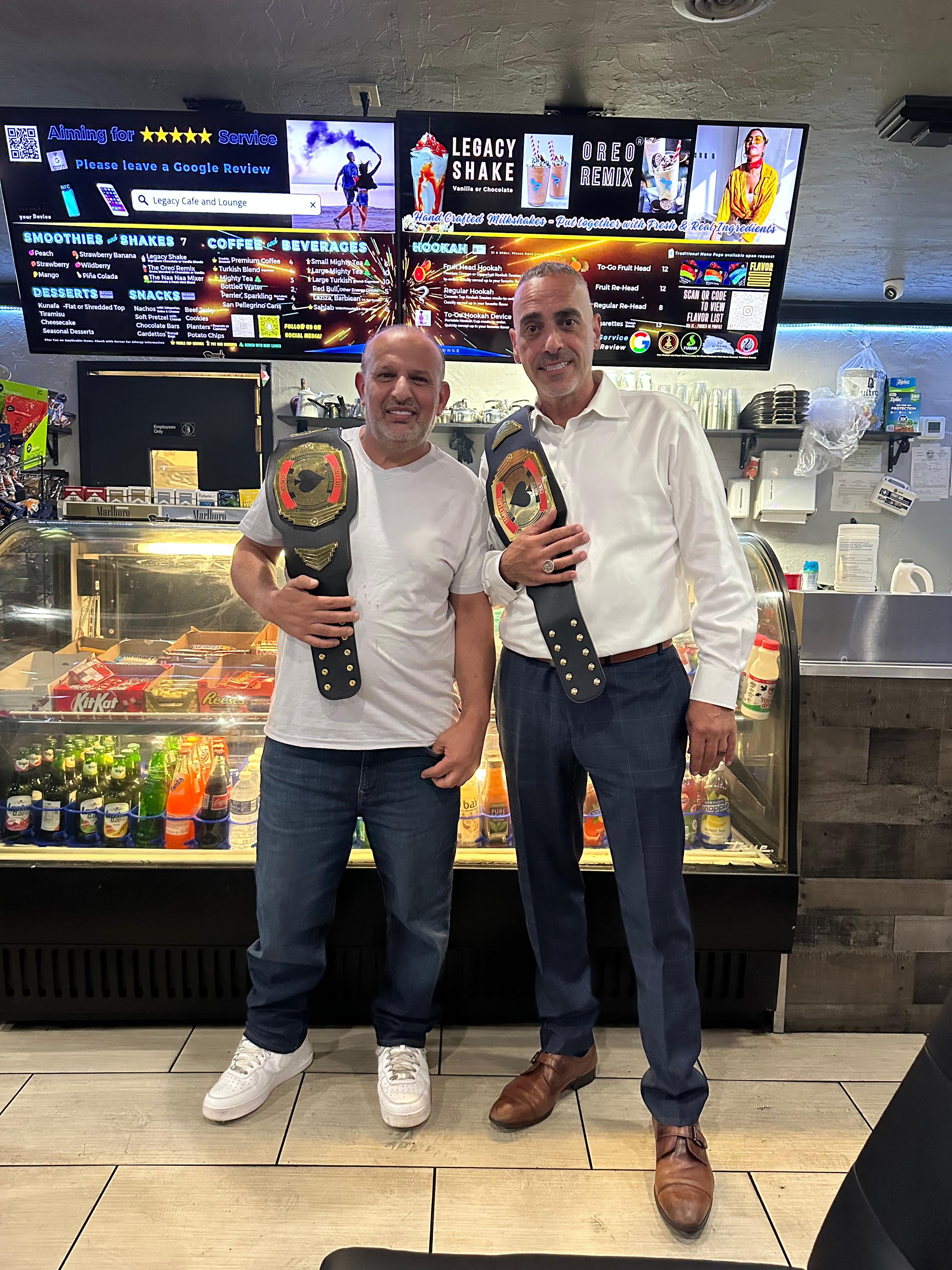Card tournament winners posing with championship belts at Legacy Cafe